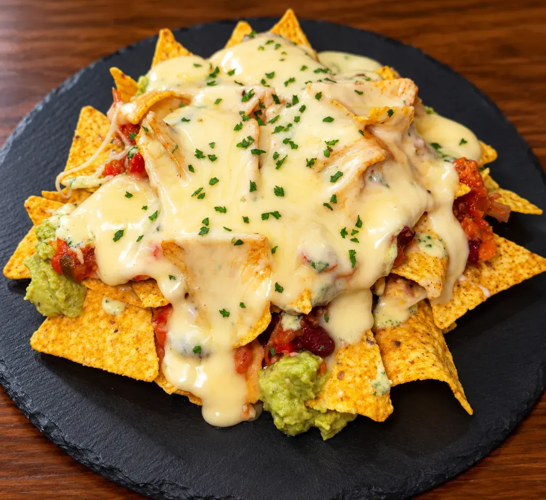 Nachos con carne mechada, frijoles, guacamole y queso fundido